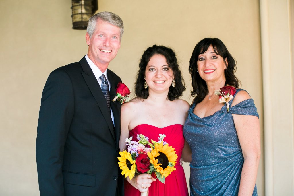 A bridesmaid with adrenal insufficiency stands proudly beside her parents at her brother's wedding.